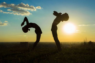 Pratik yoga gün batımı düşmesi geri parkta Çift