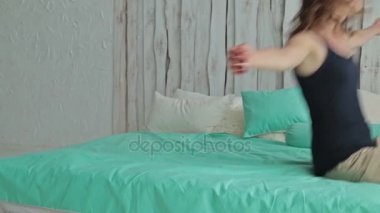 Neşeli kıvırcık kadın yatağa düşüyor. Dolly vurdu