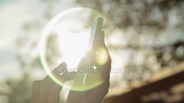 Silueta de manos de mujer con teléfono inteligente al atardecer — Vídeos de Stock