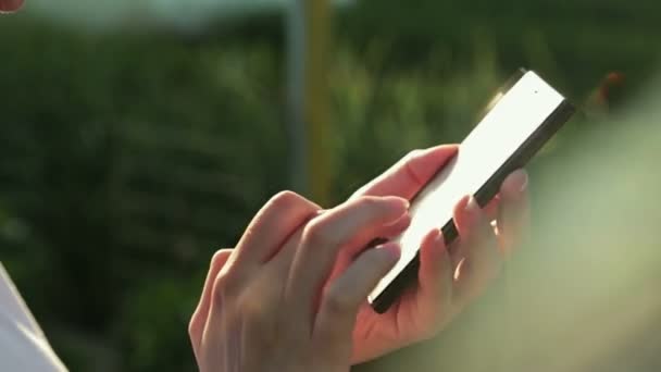 SMS femme sms en utilisant l'application sur téléphone intelligent au coucher du soleil avec éruption de lentille solaire 