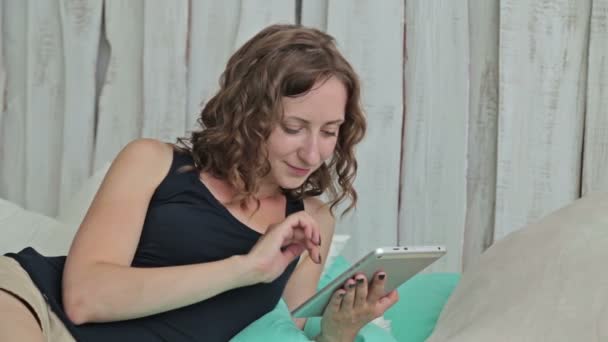 Tablet pc ile yatakta yatan genç kadın kıvırcık — Stok video