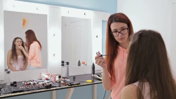 2 skott. Professionell make-up artist tillämpa mascara på ögonfransarna av modell — Stockvideo
