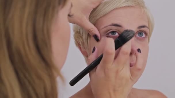 Professional make-up artist applying cream base eyeshadow primer to model eye — Stock Video