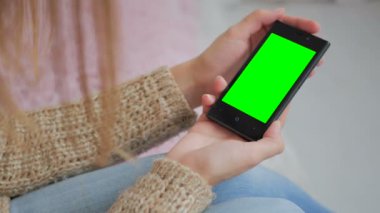 Yeşil ekranlı akıllı telefona bakan kadın