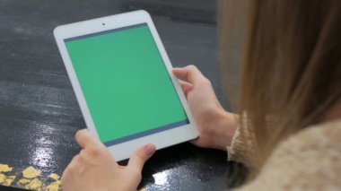 Yeşil ekranlı tablet bilgisayara bakan kadın