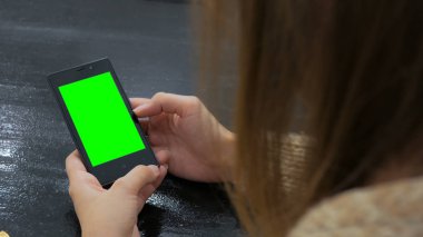 Yeşil ekranlı akıllı telefona bakan kadın
