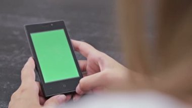 Yeşil ekranlı akıllı telefona bakan kadın