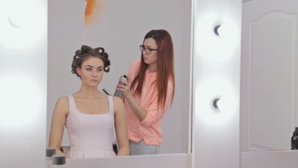 Cabeleireiro profissional fazendo penteado para jovem mulher bonita — Vídeo de Stock