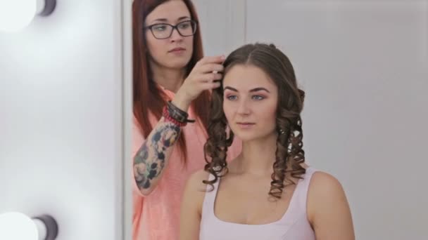 Cabeleireiro profissional fazendo penteado para jovem mulher bonita — Vídeo de Stock