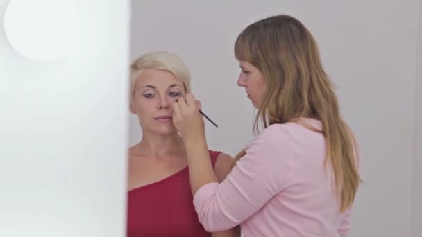Dois tiros. Maquiagem profissional artista aplicando eyeliner em torno de todo o olho do modelo — Vídeo de Stock