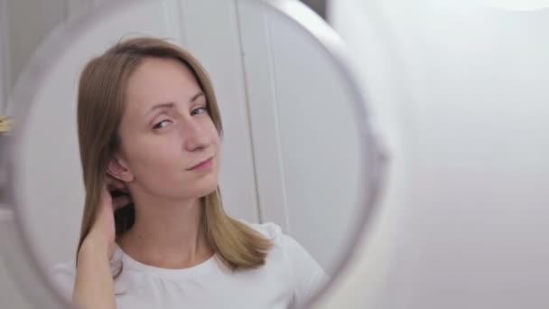 Молода красива жінка розчісує волосся перед дзеркалом — стокове відео