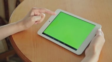 Kafede yeşil ekranlı tablet bilgisayar arayan kadın