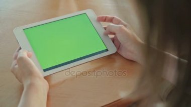 Kafede yeşil ekranlı tablet bilgisayar arayan kadın