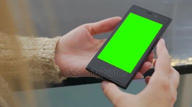 Yeşil ekranlı akıllı telefona bakan kadın