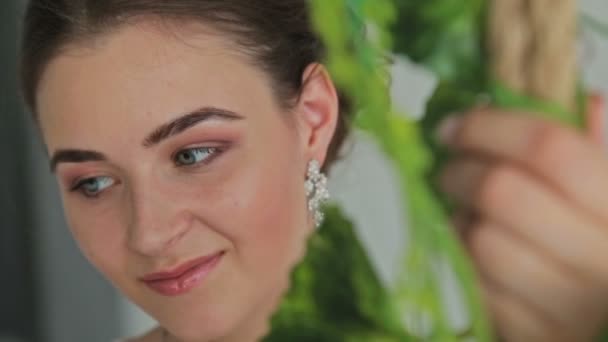 Frau mit wunderschönem Make-up und Frisur auf einer mit Blumen verzierten Schaukel. — Stockvideo