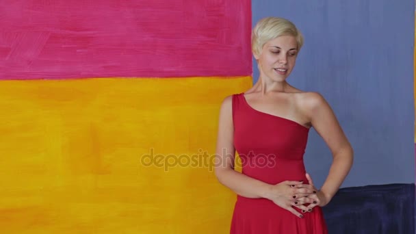 Ładna, młoda i blond kobieta w czerwonej sukience bez makijażu, patrząc na kamery — Wideo stockowe