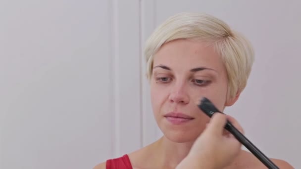Художник-макіяж наносить рідкий тональний фундамент на обличчя жінки — стокове відео