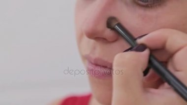 Atış kapatın. Makyöz şehvetli modeli yüzünde makyaj uygulamak