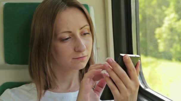 Jonge vrouw met mobiele zittend op de trein — Stockvideo