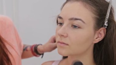 Atış kapatın. Toz kadın yüzüne uygulama profesyonel makyaj sanatçısı