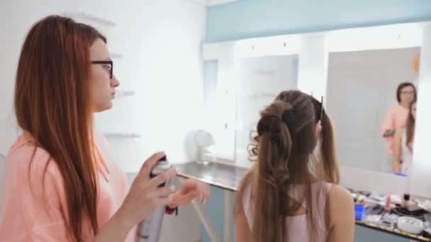 Peluquería haciendo peinado para mujer bonita joven y el uso de spray para el cabello — Vídeos de Stock