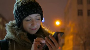 Smartphone şehirde geceleri kullanan genç güzel kadın