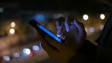 Smartphone şehirde geceleri kullanan genç güzel kadın
