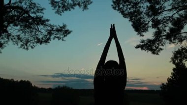 Mutlu genç kadın silueti gökyüzüne karşı ellerini havaya kaldırdı