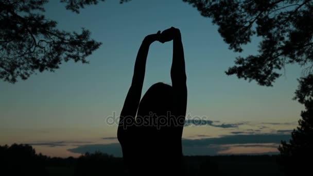 Mulher jovem que se estende em direção ao céu na floresta após o pôr do sol — Vídeo de Stock