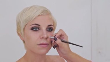 Atış kapatın. Makyöz şehvetli modeli yüzünde makyaj uygulamak