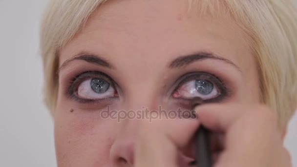 Um tiro de perto. Maquiagem artista aplicando eyeliner em torno de todo o olho do modelo — Vídeo de Stock