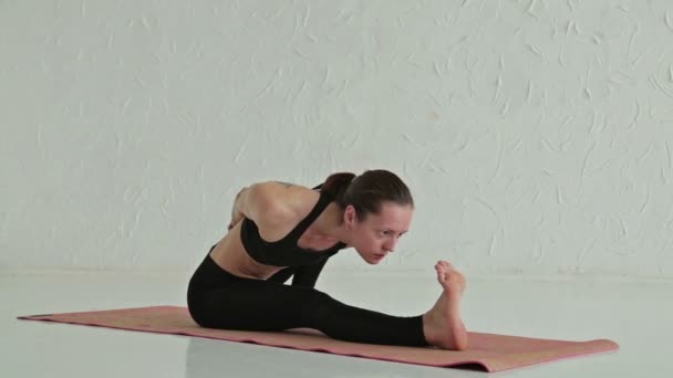 Молодая спортсменка занимается йогой в фитнес-студии — стоковое видео