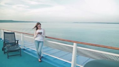 Tablet cruise gemi güvertesinde güneş doğarken kullanan kadın