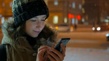 Smartphone şehirde geceleri kullanan genç güzel kadın