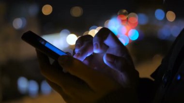 Smartphone şehirde geceleri kullanan genç güzel kadın