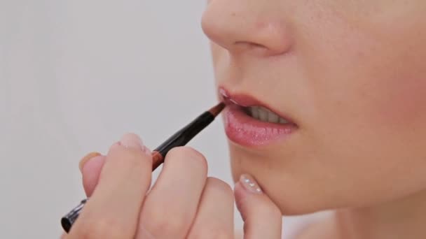 Primer plano. Artista de maquillaje profesional aplicando lápiz labial en los labios del cliente — Vídeos de Stock
