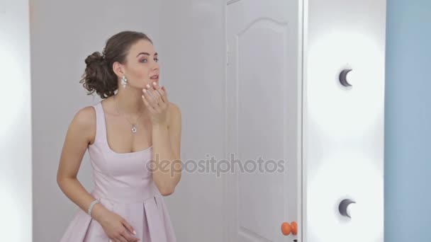 Szép nő nézi a tükörképét a tükörben, smink haj rögzítése — Stock videók