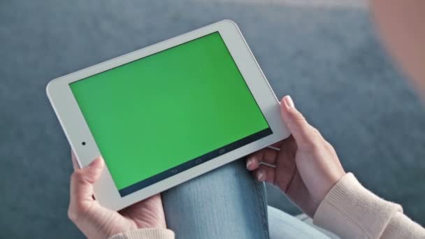 Vrouw op zoek naar een tablet met groen scherm — Stockvideo