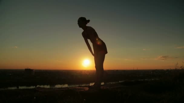 Жінка практикує йогу в парку на заході сонця — стокове відео