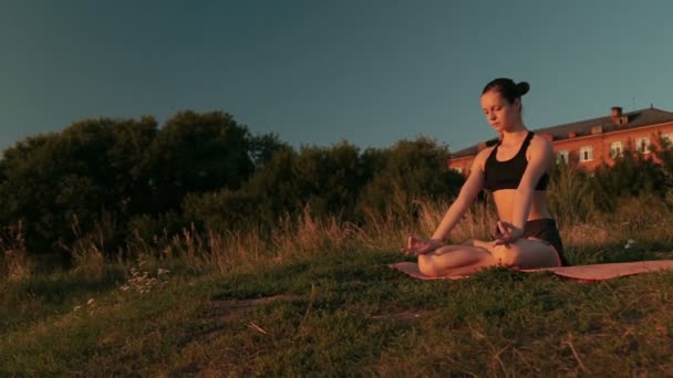 Σπορ γυναίκα σε θέση lotus στο πάρκο στο ηλιοβασίλεμα — Αρχείο Βίντεο
