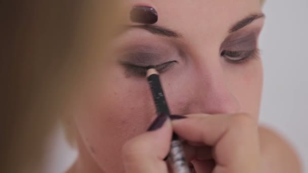 Κοντινό πλάνο. Make-up artist εφαρμογή eyeliner γύρω από το ολόκληρο μάτι του μοντέλου — Αρχείο Βίντεο