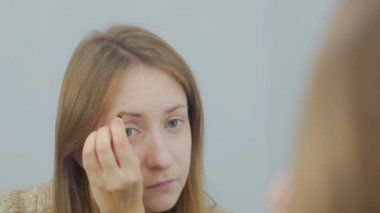 Güzel genç kadın beyaz odada kaşları çizim