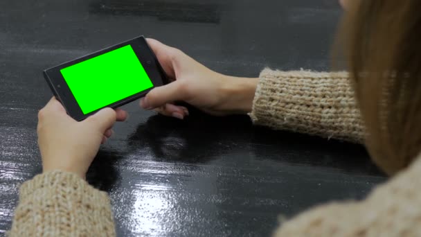 Жінка дивиться на смартфон з зеленим екраном — стокове відео