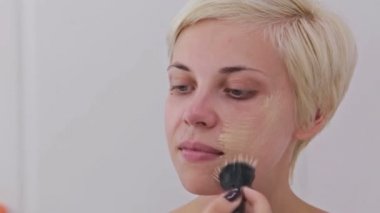 Atış kapatın. Sıvı ton temel uygulama yüzünde makyaj sanatçısı