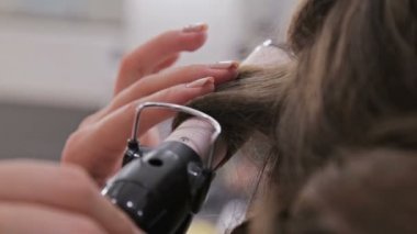 Atış kapatın. Profesyonel kuaför saç modeli için genç kadın güzel yapıyor