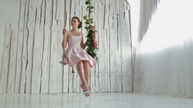 Makyaj ve saç modeli bir salıncak üzerinde güzel kadınla çiçeklerle süslenmiş.