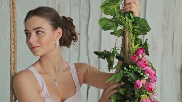3 strzały. Kobieta z makijaż i fryzurę na huśtawce ozdobione kwiatami. — Wideo stockowe