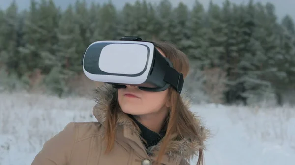 Woman using virtual reality glasses in winter forest