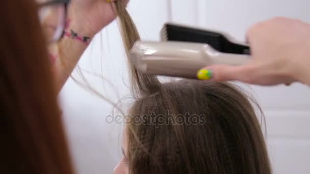 Frisören använder plattång på långt hår client i frisersalong — Stockvideo