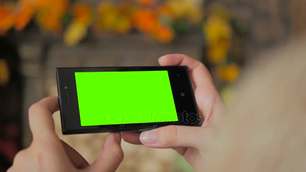 Женщина смотрит на смартфон с зеленым экраном — стоковое видео